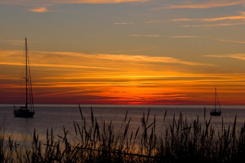 hinter den Dünen Sonnenuntergang mit zwei Segelbooten